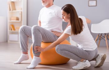 woman therapist assisting man patient during exercises on gymnastic ball atlanta, ga