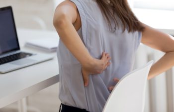 Rear close up view girl touch back feels unhealthy by uncomfortable office chair increase backpain. Sedentary work, wrong posture incorrect position, intervertebral disc, spinal joint damage concept
