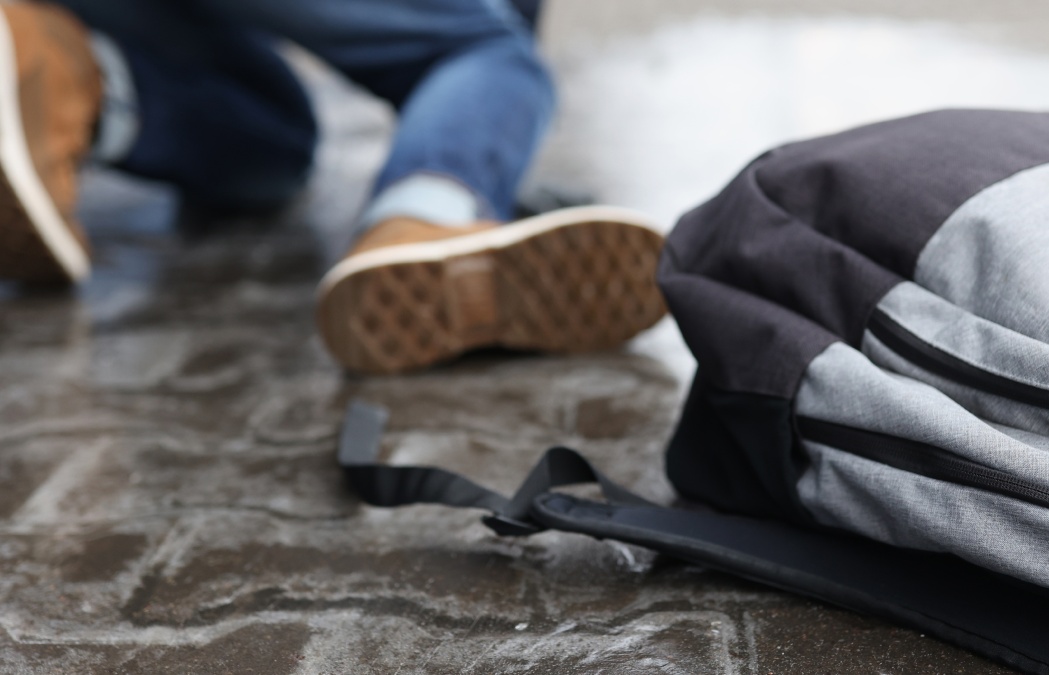 Man with backpack felling on slippery sidewalk in winter closeup