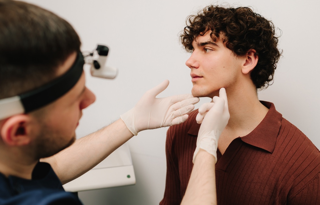 Face correction and lifting to reshape chin. Facebuilding. Doctor touching male face in protective gloves before chin shape correction with fillers