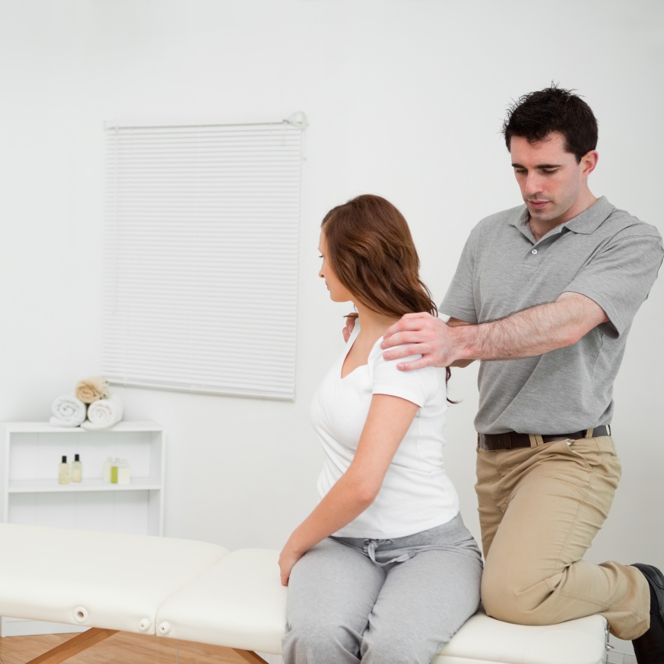 Osteopath looking at the back of a woman in a medical room