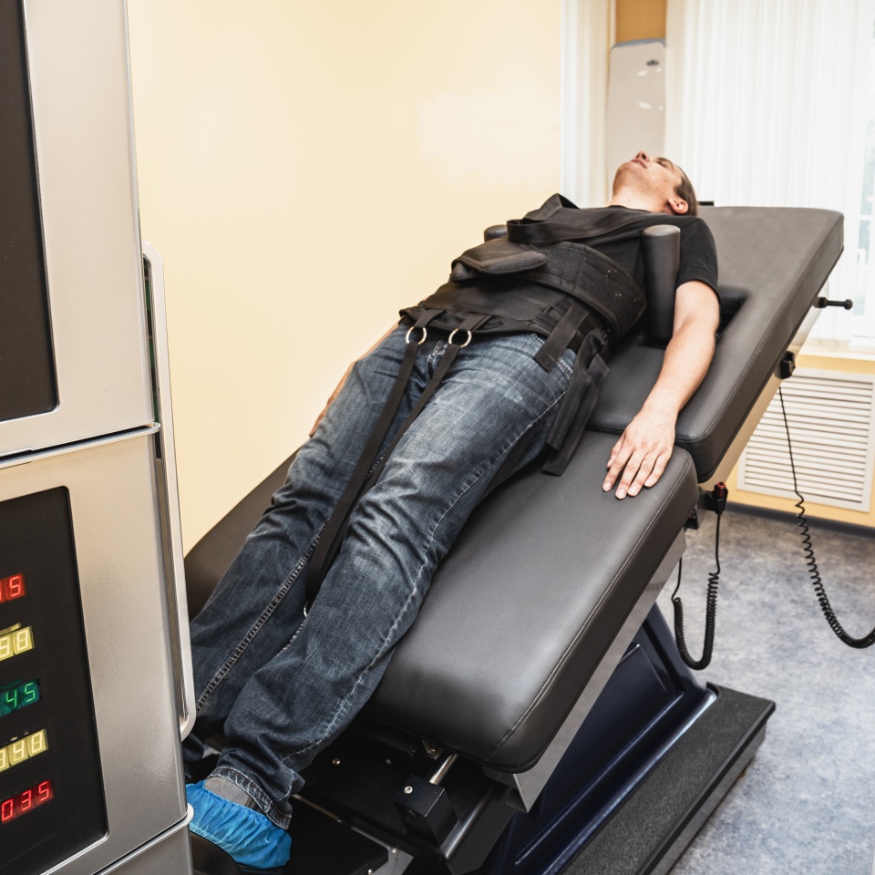 Man with problems of low back spinal hernia on stretching and decompression procedure in medical center with special equipment, orthopedic therapy.