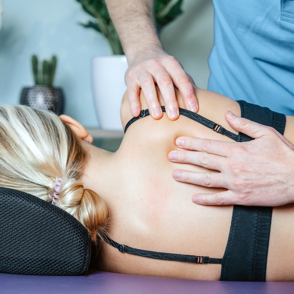 Manual therapist fixing scapular or rhomboid muscle pain with his hands, osteopath releasing trigger points and correcting joint alignment