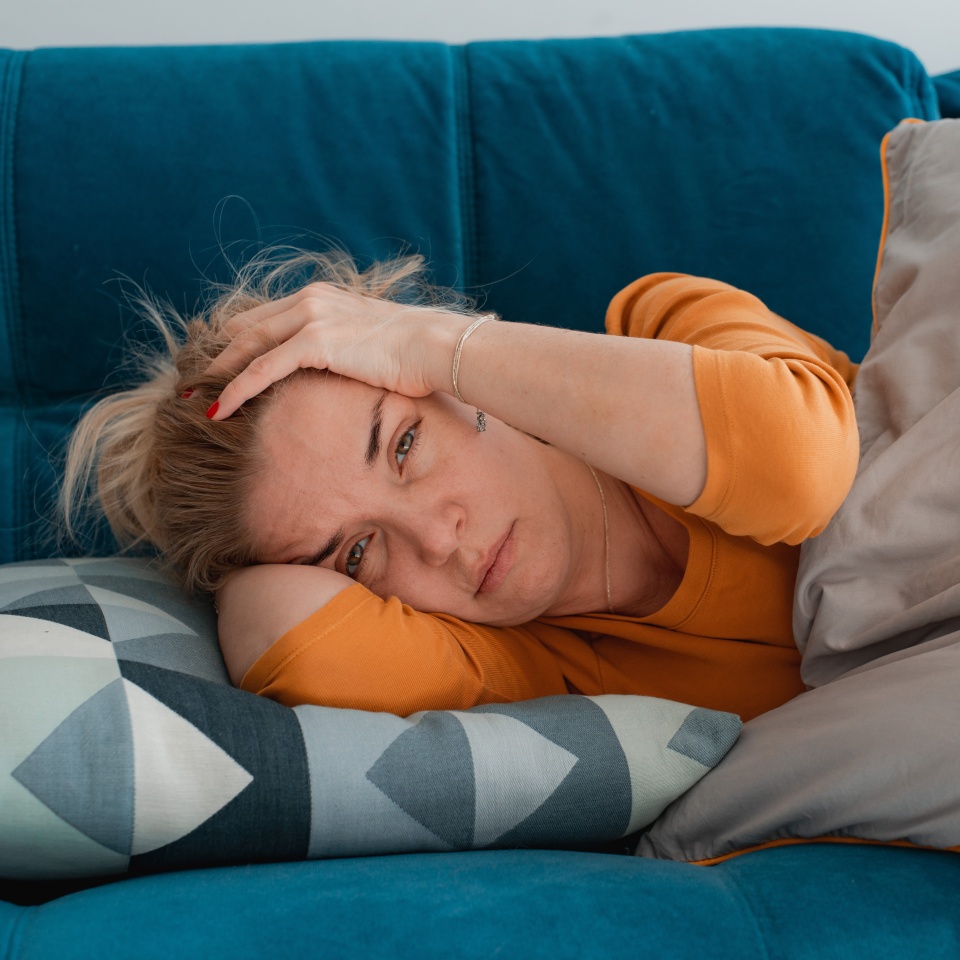 depressed mature woman lying sofa with her arms around herself, covering her head with hands, unhappy woman suffering from insomnia depression, psychological problem, concept impotence, asthenia