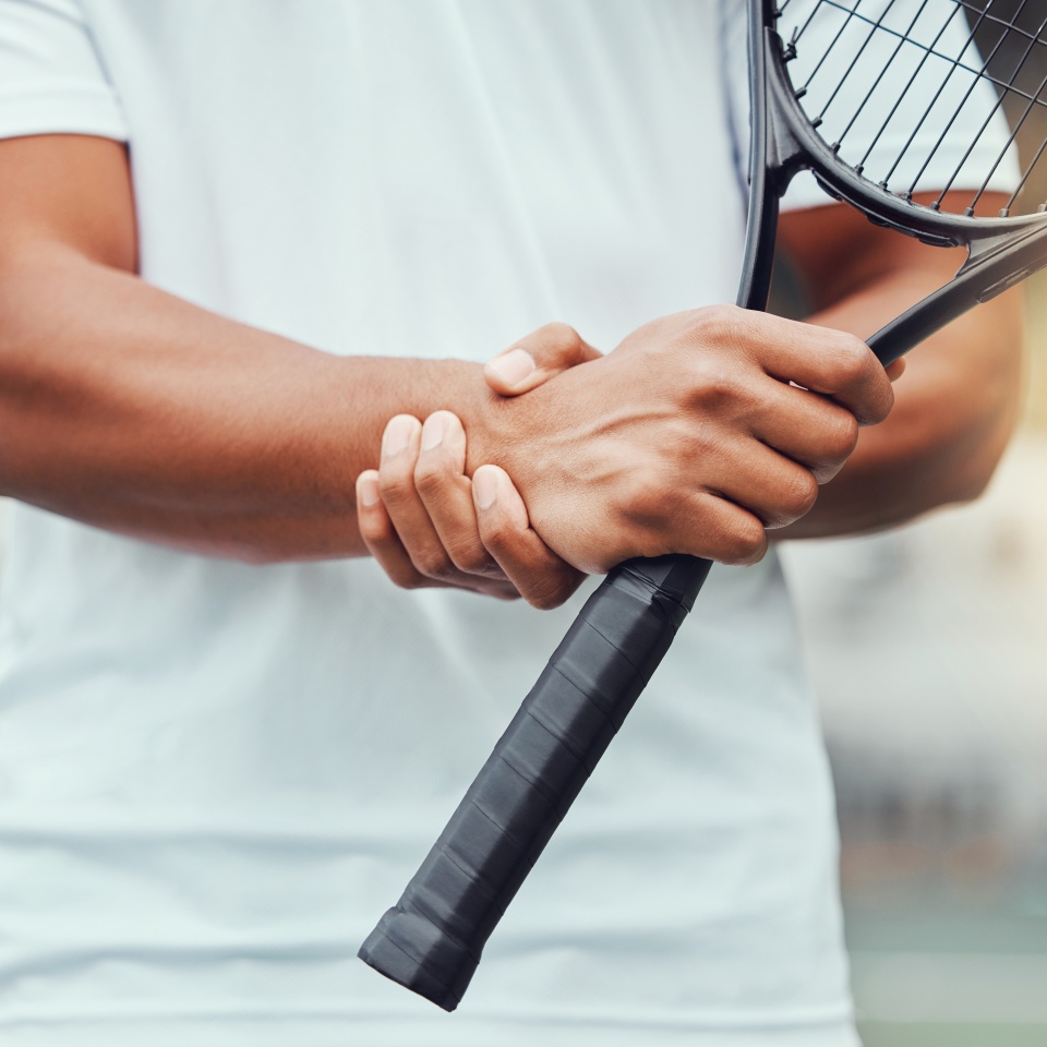 Tennis court, hand injury and man with racket for sports, fitness and match with discomfort or bruise. Joint pain, wrist and male player with arthritis, osteoporosis or fibromyalgia during training