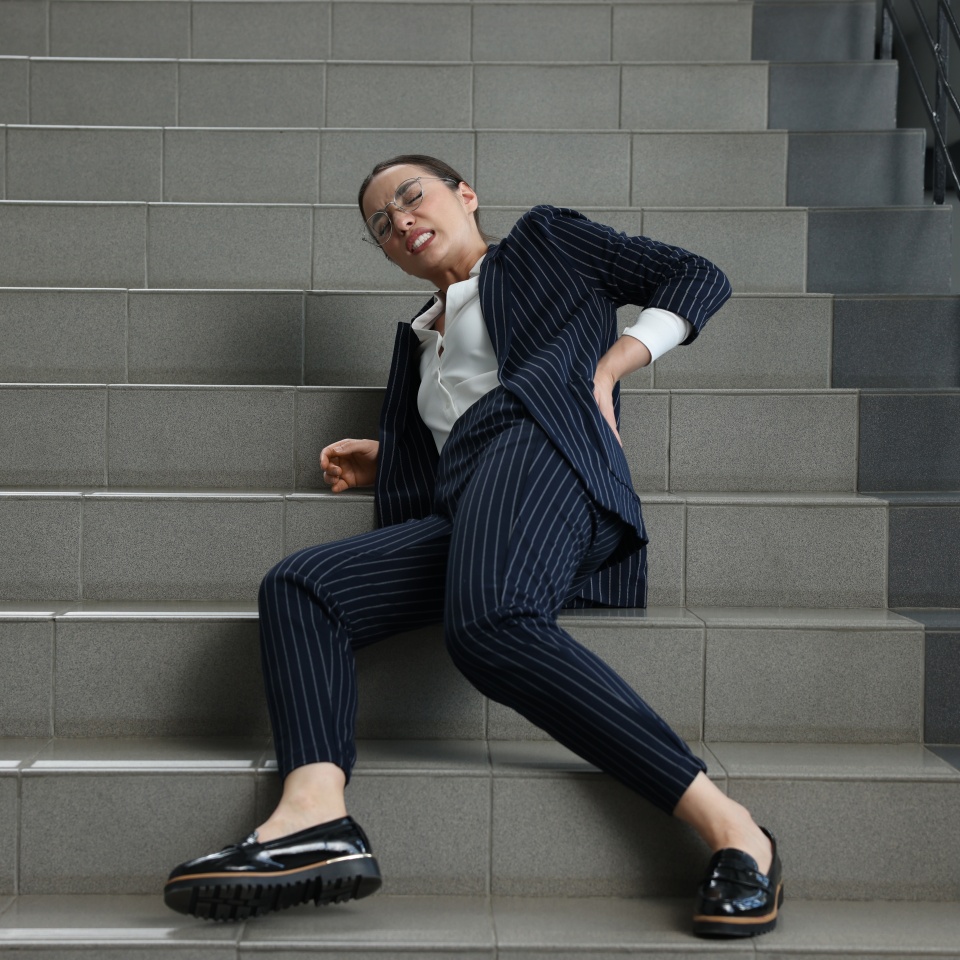 Woman fallen down stairs suffering from pain in back indoors