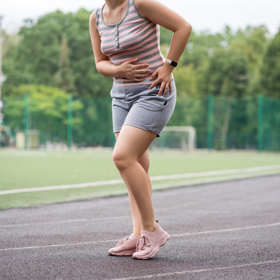 Pain in the hip during training, muscles cramped, massage on a sports ground after workout, health problems concept