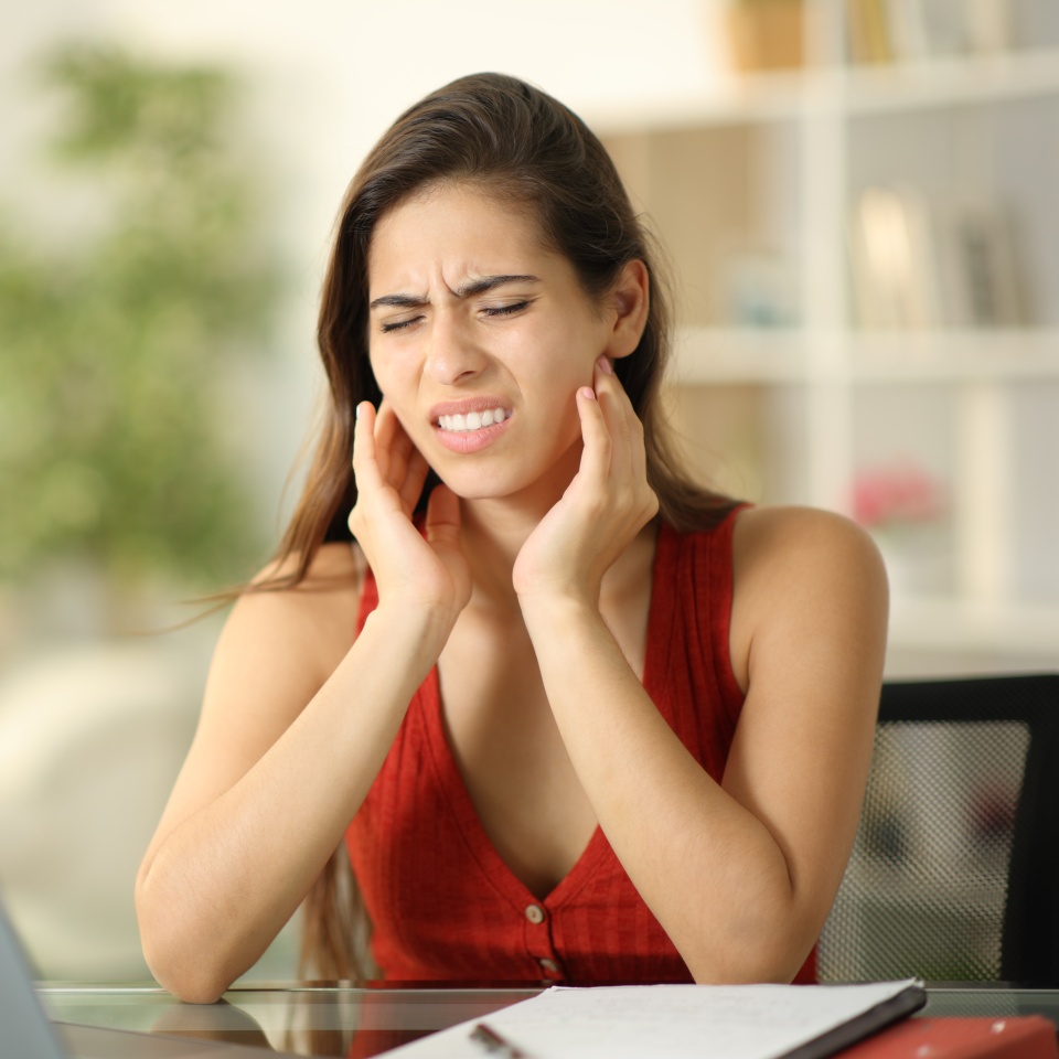Stressed student suffering temporomandibular ache at home