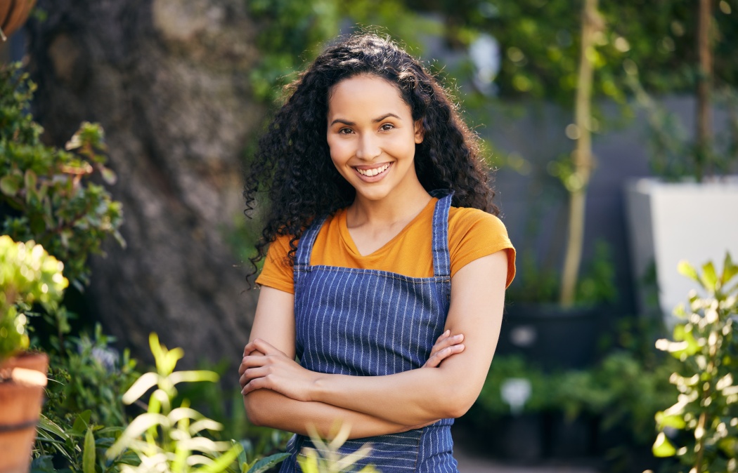 Outdoor, florist and smile for portrait, woman and entrepreneur with apron, spring and growth of plants. Small business, nature and person in garden, ecology and service for shop, green and happy