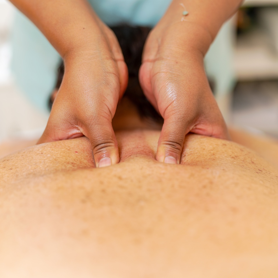 Fingers of a masseur pressuring trigger points of the back of a woman in a spa