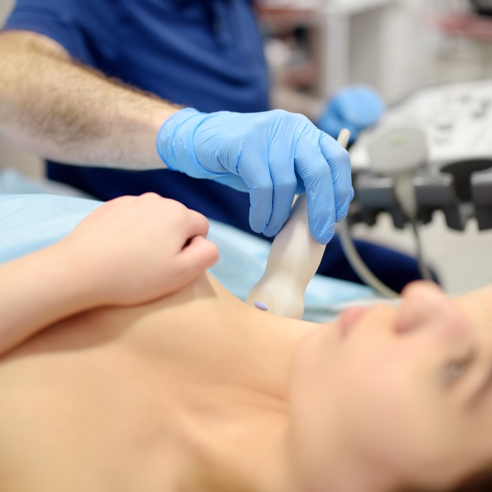Mammologist doctor examines a woman breasts and lymph nodes using ultrasound. Mammography and ultrasound scanning are main methods of instrumental diagnosis of mammary glands. Breast cancer awareness