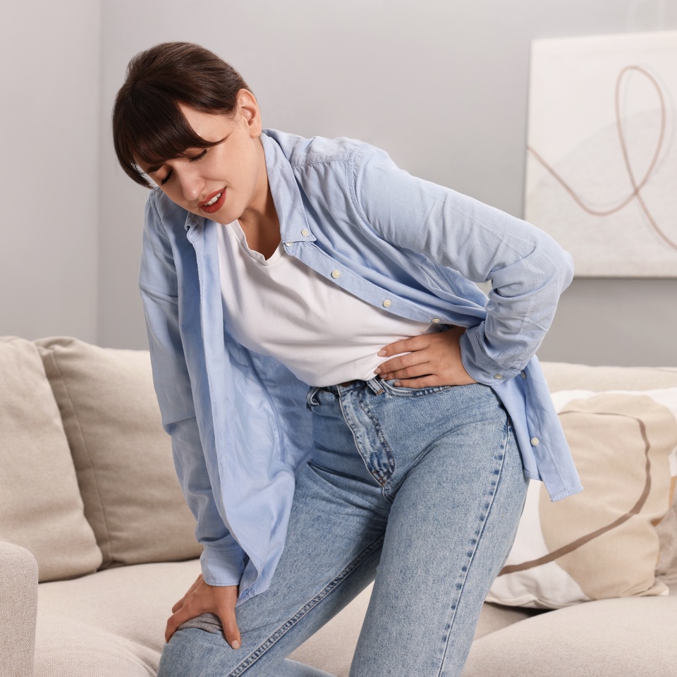 Upset woman suffering from hip joint pain at home