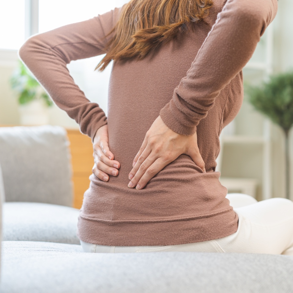 Pain body muscles stiff problem, suffer asian young woman painful back, symptom injury ache from long study work, hand holding massaging or rubbing lower back hurt, sore sitting on sofa at home.