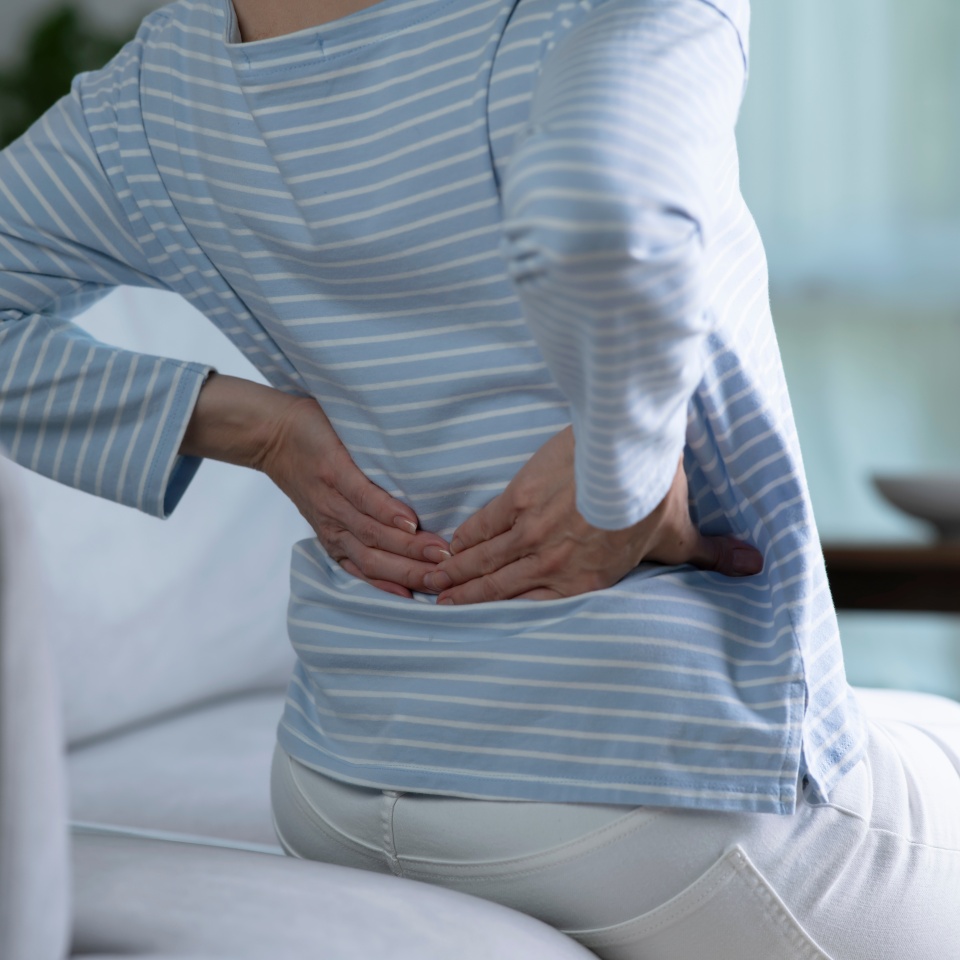 Asian senior woman on sofa feeling and suffering from back pain and lower lumbar discomfort and muscle pain wake up with backache after uncomfortable sleep concept, close up rear view
