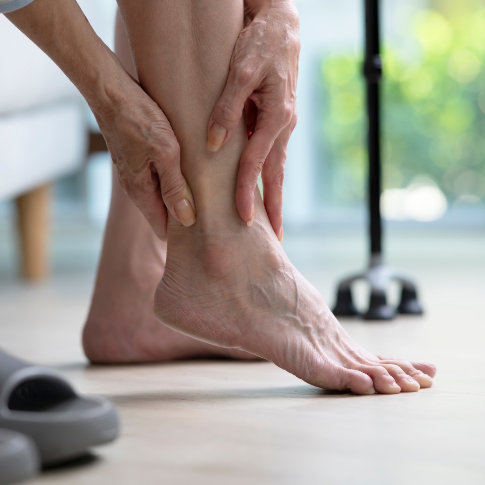 Foot pain concept, senior woman suffering from pain in ankle at home. woman rubbing, massaging sore feet area of pain, Mature woman discomfort painful feet ache from walking.