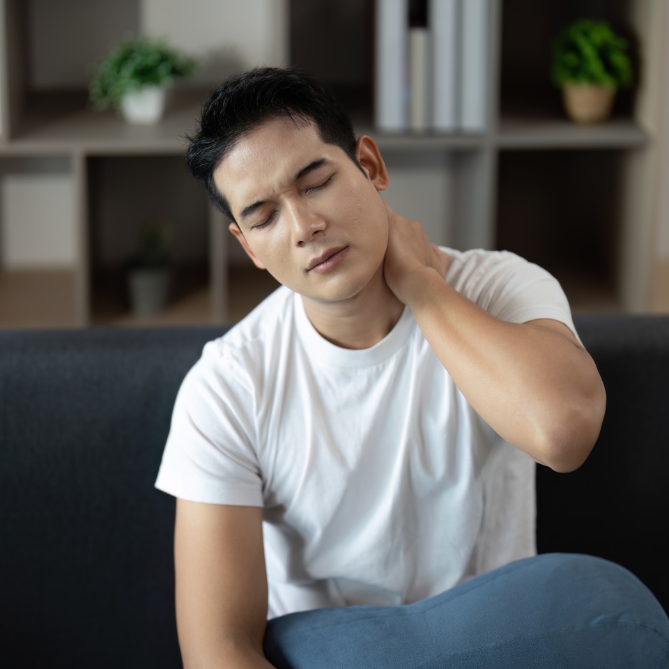Neck Pain Relief. Man rubbing neck in discomfort while seated.