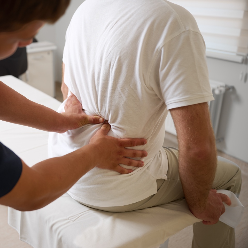 Chiropractor performing manual back adjustment on patient in medical clinic. Physiotherapy, spinal alignment, and rehabilitation treatment for lower back pain relief.