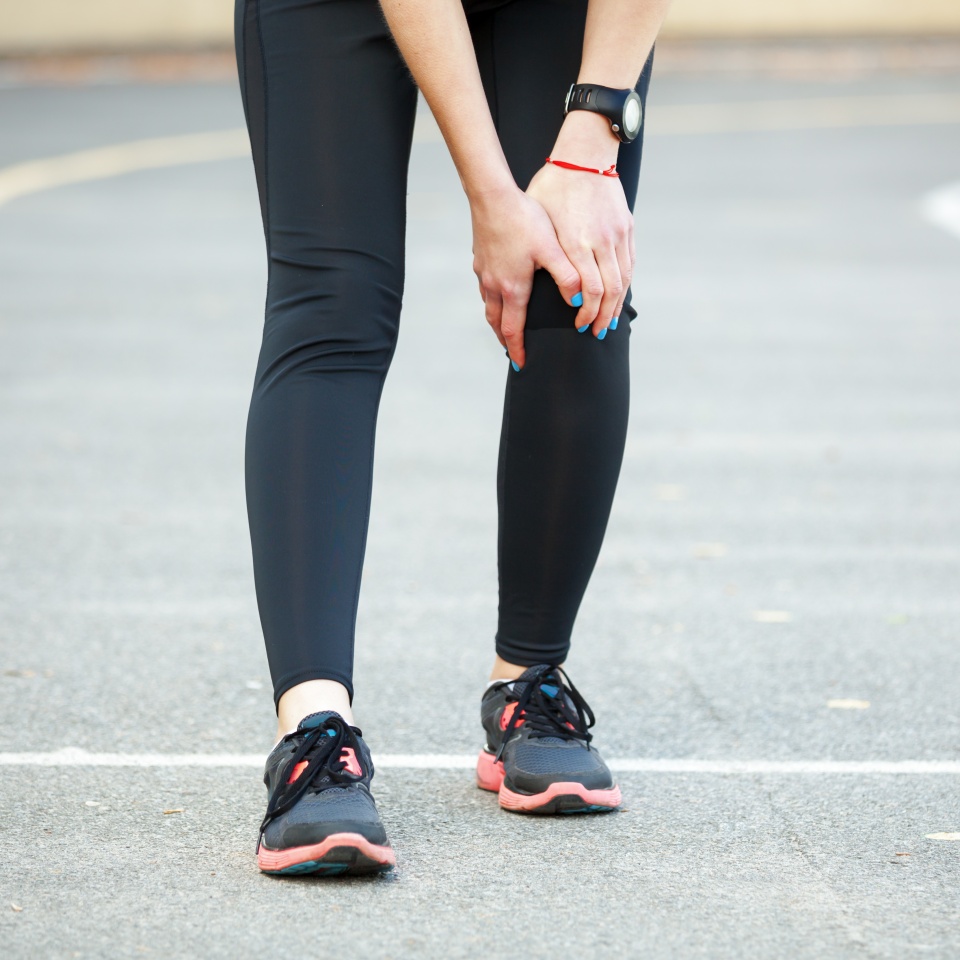 Young female runner is holding her injured leg. Knee problems.