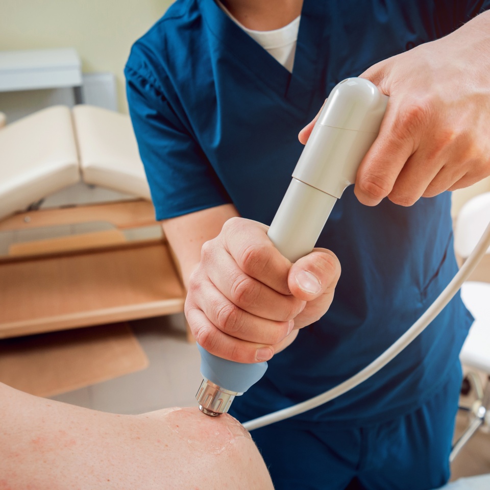 Shock wave therapy. The magnetic field, rehabilitation. Physiotherapist doctor performs surgery on a patient's shoulder